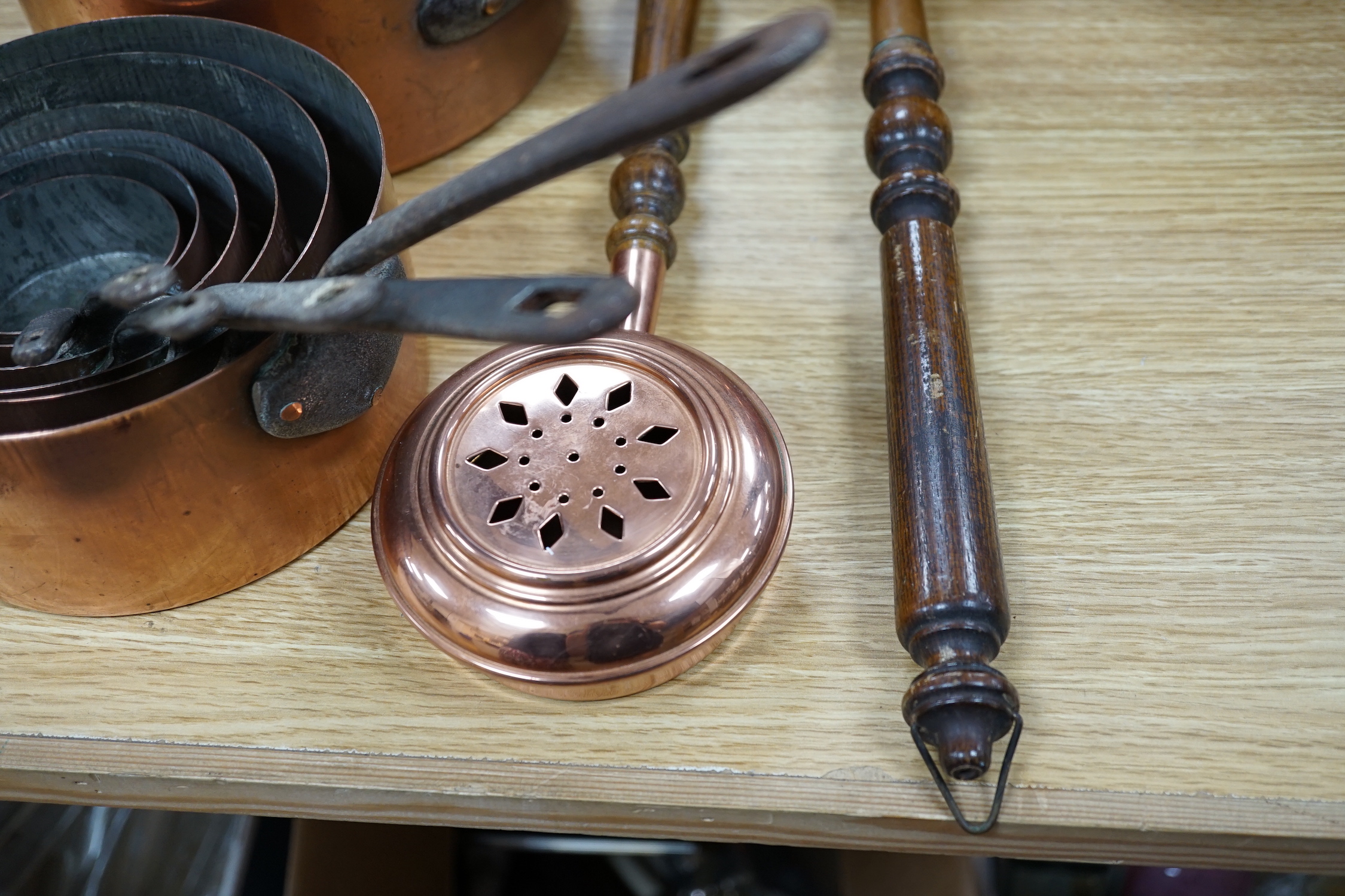 A quantity of various copper-ware including graduated pans, lidded cauldron and miniature warming pans, largest 39cm wide